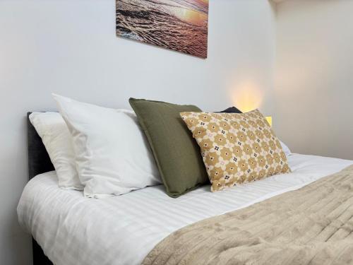 a bed with white and green pillows on it at 4 Bed Contractor Apartment with Parking Central Banbury in Banbury