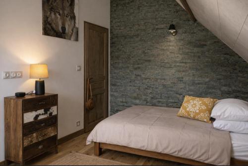 a bedroom with a bed and a brick wall at Villa MYRTILLE classée 4 étoiles meublé de tourisme - Vue montagne, terrasse, jardin, 8 pers in Murat-le-Quaire