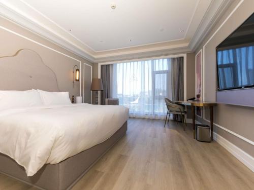 a hotel room with a large bed and a desk at Mercure Turpan Downtown in Turfan