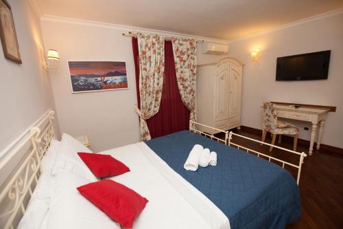 a bedroom with a bed with red pillows and a desk at Hotel Ausonia in Naples