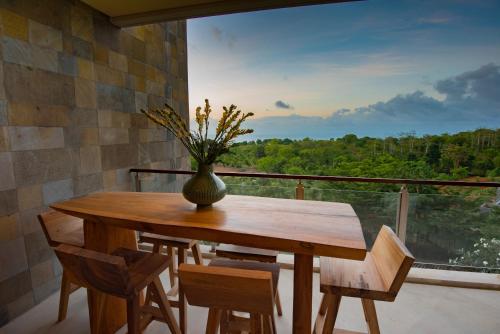 a wooden table with chairs and a vase with flowers at Luxury Apartment at AYANA Residences in Jimbaran