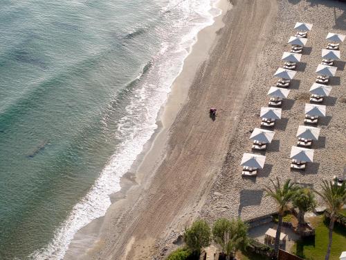 Eine Draufsicht auf einen Strand mit Sonnenschirmen und dem Meer in der Unterkunft Amirandes, A Resort to Live in Gouves