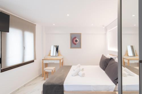 ein weißes Schlafzimmer mit Bett und Spiegel in der Unterkunft Anassa Suites 3 in Iraklio