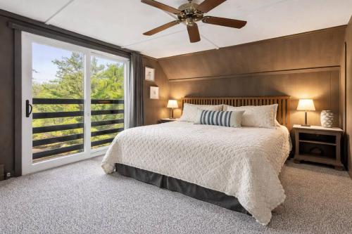 a bedroom with a bed with a ceiling fan and a window at Little Longbow Lakefront Chalet in Becket