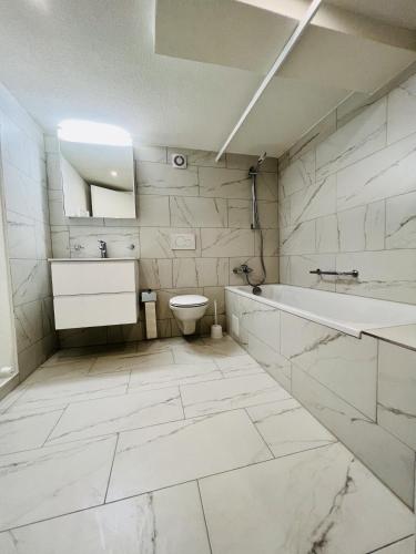 a white bathroom with a tub and a toilet at Gemütliches Wohnung für Familien und Gruppen in Küblis