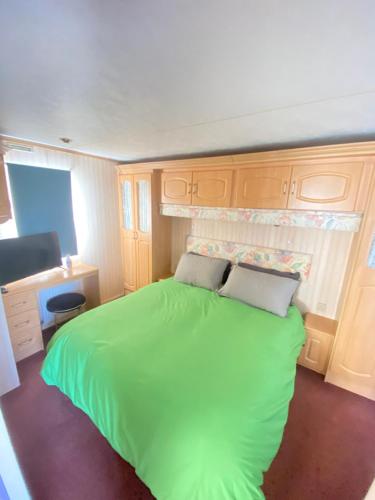 a bedroom with a green bed and a desk at PD Wonderwall Caravan, Direct beach access & Beds made on arrival & GCH in Ingoldmells