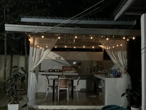 a patio with a table and chairs and lights at The Siblings Farm House in Liliw