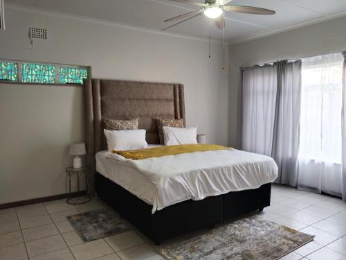a bedroom with a large bed and a ceiling fan at Five-Bedroom House at 27 Baobab Avenue, Birchleigh, Kempton Park, Backup Power Supply in Kempton Park