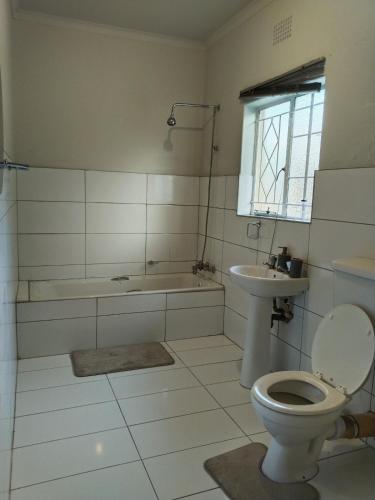 a bathroom with a toilet and a tub and a sink at Five-Bedroom House at 27 Baobab Avenue, Birchleigh, Kempton Park, Backup Power Supply in Kempton Park