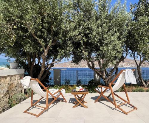 two chairs and a table on a patio with trees at Sunset Villa in Posidhonía