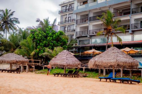 a beach with chairs and umbrellas and a building at Lavanga Beach in Hikkaduwa