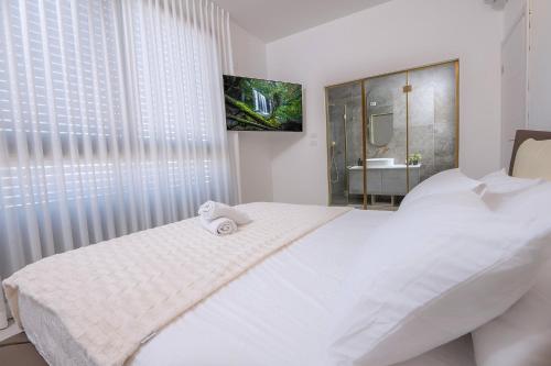 a white bedroom with a large white bed and a window at רויאל טווינס בוטיק in Safed