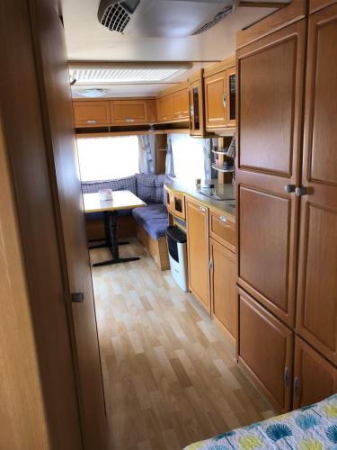 a small kitchen with wooden cabinets and a table at Caravane revisité in Pleslin-Trigavou
