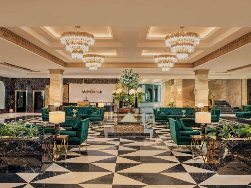 a lobby with green furniture and chandeliers at Mövenpick Cairo Media City in 6th Of October