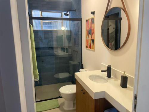 a bathroom with a toilet and a sink and a mirror at Incrível apto com banheira e garagem perto de tudo in Florianópolis