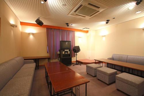 a living room with couches and tables and a tv at Shiki Resort Hida Takayamaso in Takayama