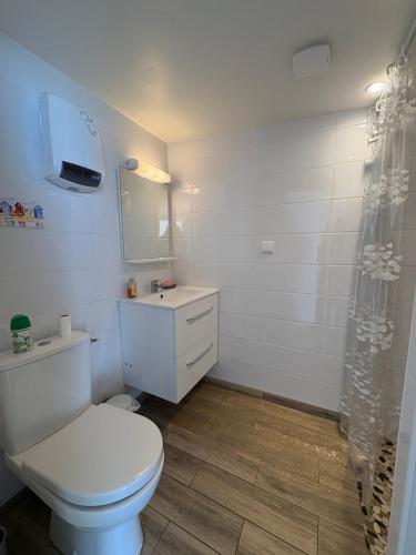 a white bathroom with a toilet and a sink at La cabine de plage in Batz-sur-Mer