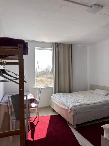 a bedroom with a bed and a desk and a window at Infinity Hotel in Cholpon-Ata