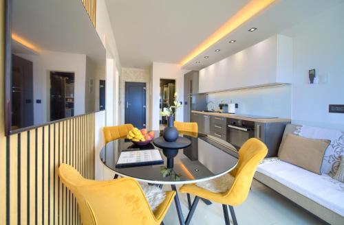 a kitchen and living room with a glass table and yellow chairs at Apartments Sinisa - City of Krk in Krk