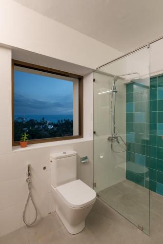 a bathroom with a toilet and a glass shower at The Loft Mirissa in Mirissa
