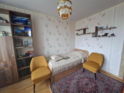 a bedroom with a bed and two chairs at Prie Masčio ežero in Telšiai