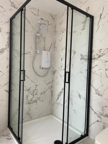 a shower with a glass door in a bathroom at Seaside Suite Quilty in Quilty