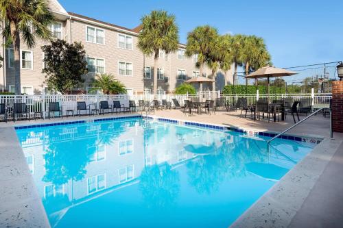 a large swimming pool with tables and chairs next to a building at Residence Inn by Marriott Fort Myers in Fort Myers