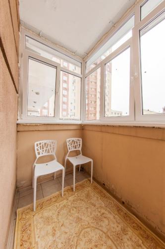 two white chairs in a room with windows at Botanic Towers the house has a shelter in Kyiv