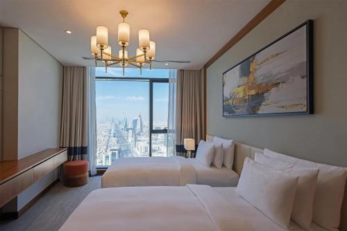 a hotel room with two beds and a large window at Radisson Collection Residences, Riyadh in Riyadh