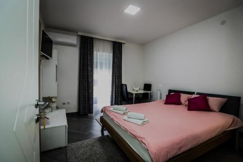 a bedroom with a large bed with pink sheets at Apartman Lena lux in Vrnjačka Banja