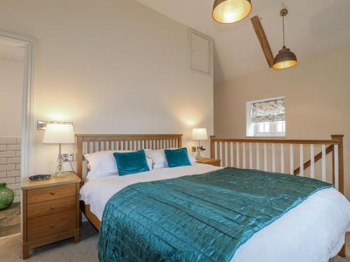 a bedroom with a large bed with blue pillows at The Granary Barn at America Lodge in Oakham