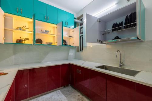a kitchen with red and green cabinets and a sink at Yashobhoomi Suites near Yashobhoomi Convention Centre in New Delhi