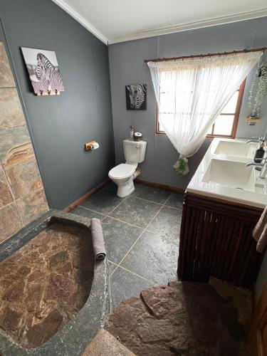 a bathroom with a tub and a toilet and a sink at Boskoors in Hammanskraal