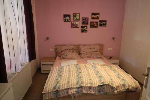 a small bedroom with a bed with pink walls at Szántó Villa in Hévíz
