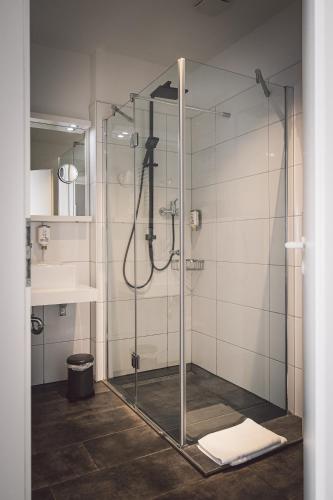 a shower with a glass door in a bathroom at Hotel Alte Redaktion in Gevelsberg