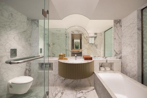 a bathroom with a tub and a sink and a toilet at Le Meridien, Surat in Surat