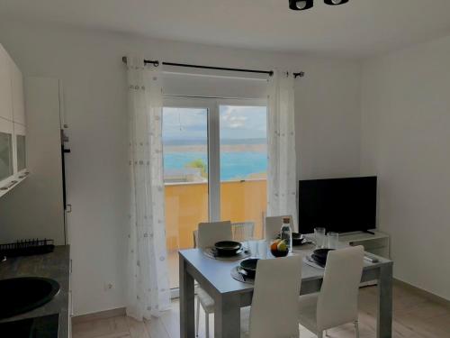 a dining room with a table and chairs and a window at Valuna - Modern Sea View Apartment -Terrace - 4 Min to Beach - Free Parking in Jadranovo