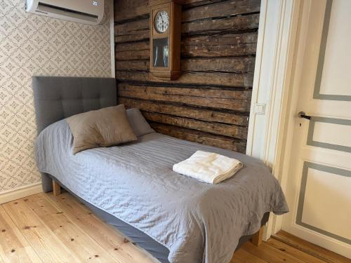 a bed in a bedroom with a clock on the wall at Nedanby | Cottage | Idyllic location | Porch | Grill in Edsbro