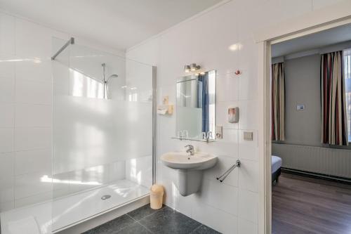 a white bathroom with a sink and a shower at New Hotel de Lives in Namur