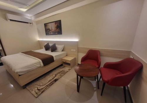 a bedroom with a bed and two red chairs at Hotel Ananta Vilas in Khurja