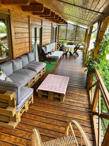 a porch of a cabin with a couch and a table at Agroturystyka Ranczo Turzyniec w pobliżu Zwierzyńca in Turzyniec