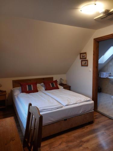a bedroom with a bed with white sheets and red pillows at Berki Vendéglő és Hotel in Körmend