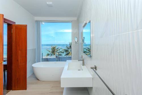 a bathroom with a tub and a sink and a window at Iconic Polhena in Matara