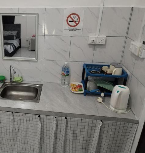 a kitchen counter with a sink and a mirror at Homestay Rezquna Deluxe Studio in Beaufort