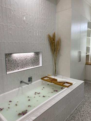a white bathroom with a bath tub with a plant at The Guesthouse in Terang