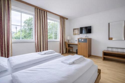 a hotel room with two beds and a desk at Mühlengarten by Zzzimple in Nittel