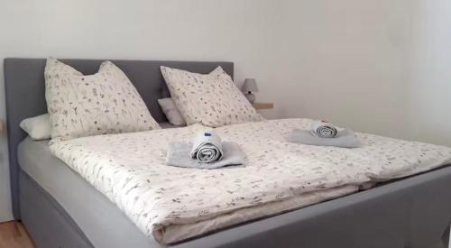 a bed with white sheets and two controllers on it at Hilla's Traumhaus in der Eifel in Schleiden