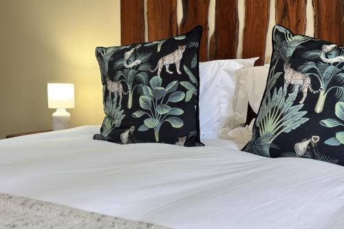 a bed with black and white pillows on it at Wild Haven Lodge in Victoria Falls