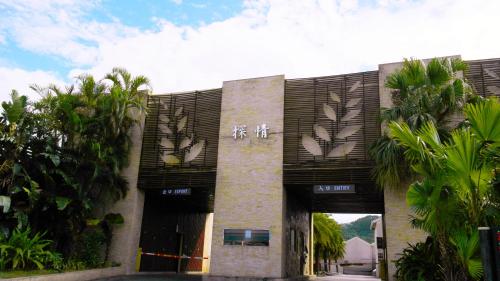 a building with a gate and palm trees in front of it at Discovery Motel - Tucheng in Tucheng