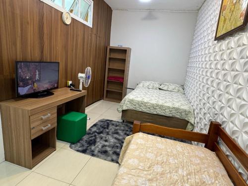a bedroom with two beds and a desk with a television at Interlagos Family House in São Paulo